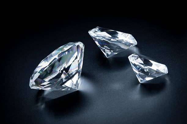 Photo of three various sizes diamonds scattered on black background.